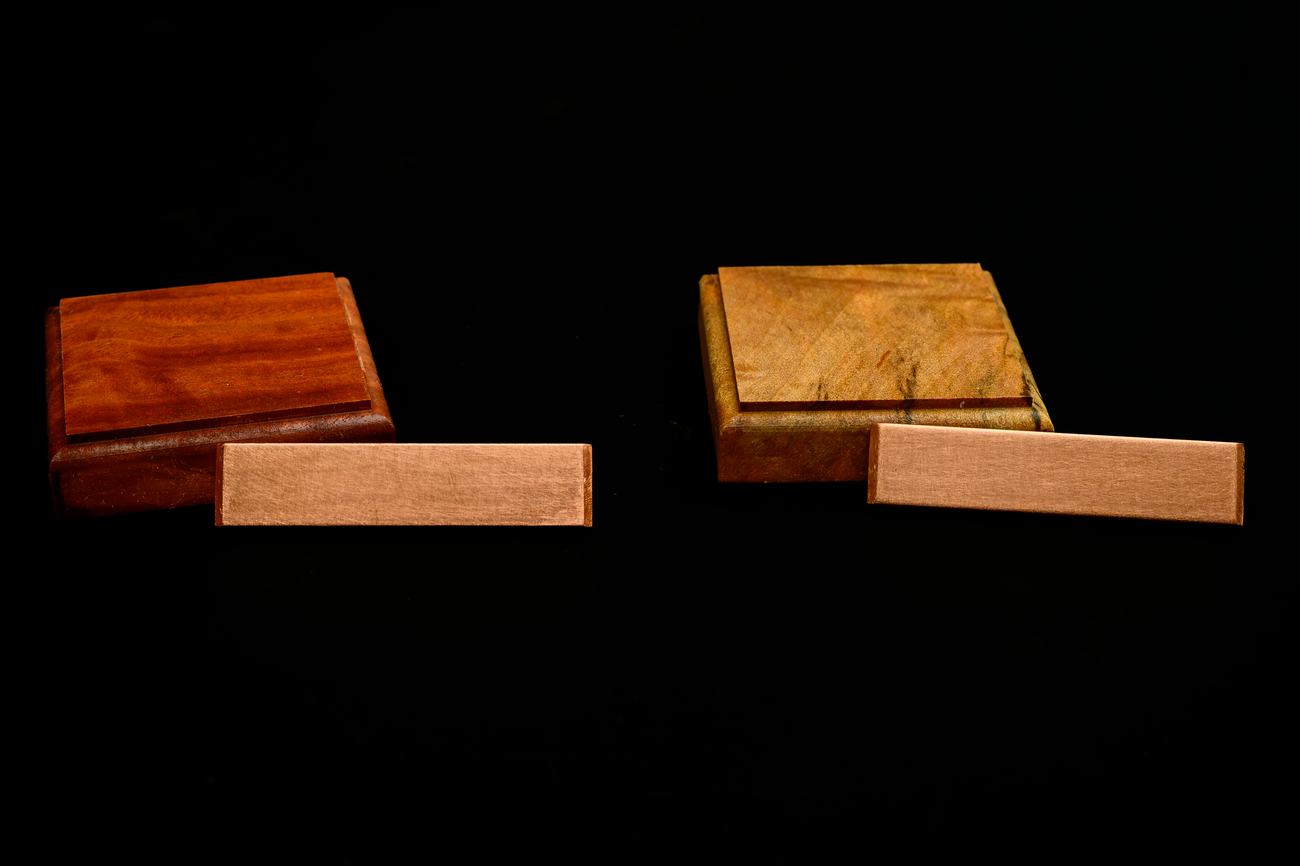 Two wood tiles fitted with an angled length of copper spline at their mitred corner