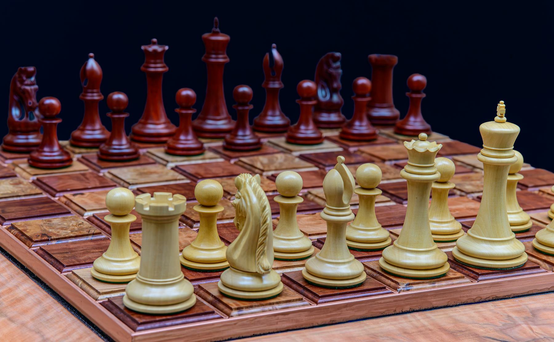 Close-up of light-coloured chess pieces facing dark opponents across the board